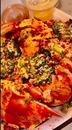 Close-up of crab legs topped with seasoning, herbs and sauce