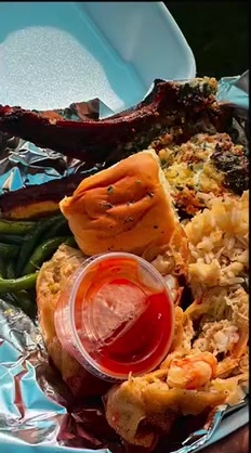 Foil tray with lamb chops, green beans and a crab-topped seafood portion