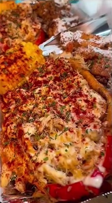 Loaded seafood dish topped with cheese, seasoning and herbs, served with corn